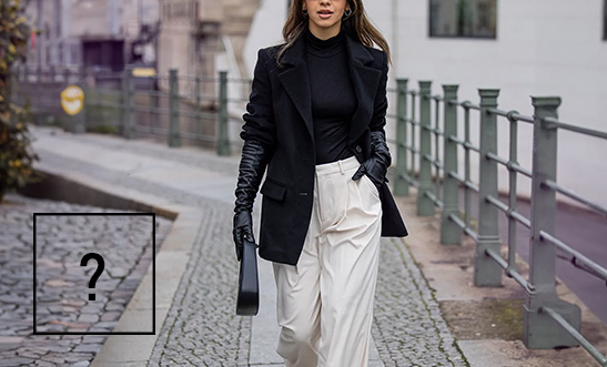 Žena v čiernom kabáte a bielych širokých nohaviciach